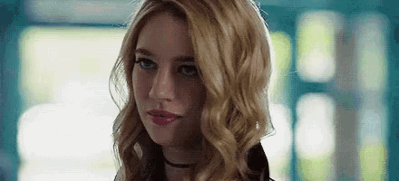 a woman with blonde hair and a choker is looking at the camera .