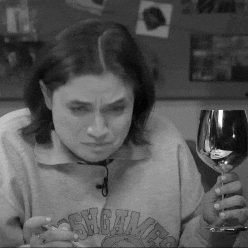 a woman wearing a sweatshirt that says shotguns is holding a glass