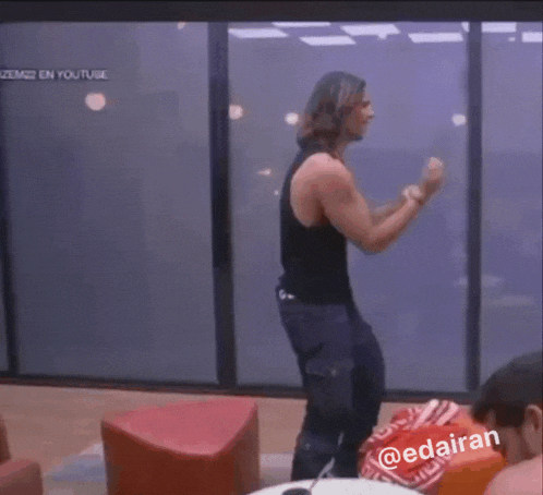 a man in a black tank top is dancing in front of a screen that says youtube