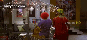 a man and a woman are standing in a living room . the woman is wearing a red wig .