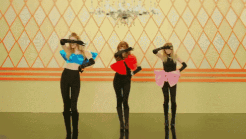 three women dancing in front of a wall with a chandelier