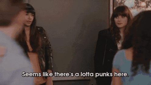 a group of people are standing around a woman who says " seems like there 's a lotta punks here . "