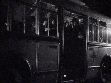 a man in a hat and coat is standing in front of a train