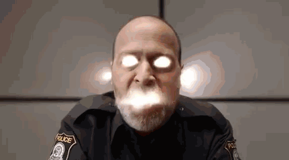 a police officer is making a funny face with his eyes glowing in the dark .
