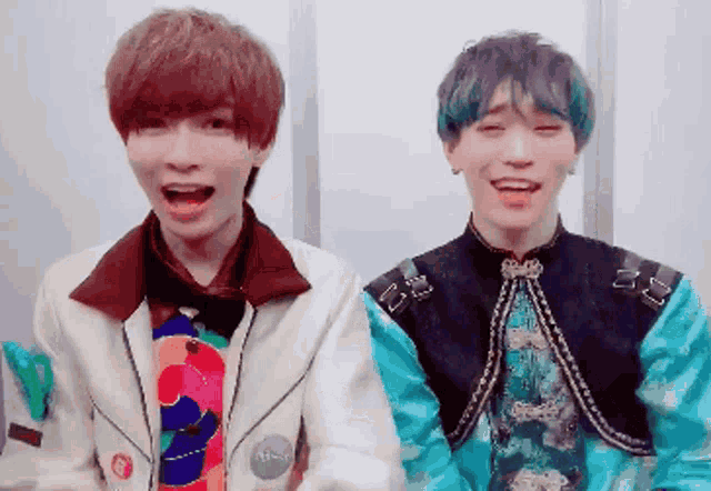 two young men are standing next to each other and laughing .