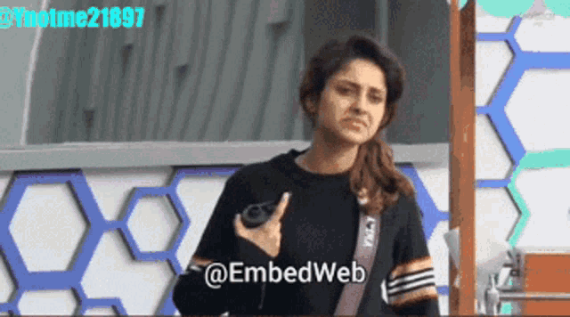 a woman in a black sweater is standing in front of a wall that says embedweb