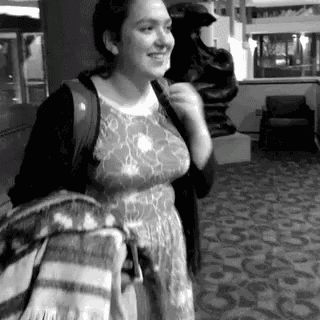 a woman in a dress is standing in a hallway holding a blanket .