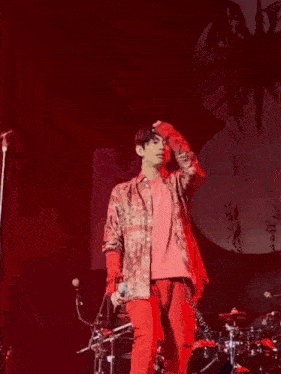 a man in a red shirt is holding a microphone on a stage .