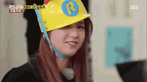 a woman is wearing a yellow hard hat with the letter r on it