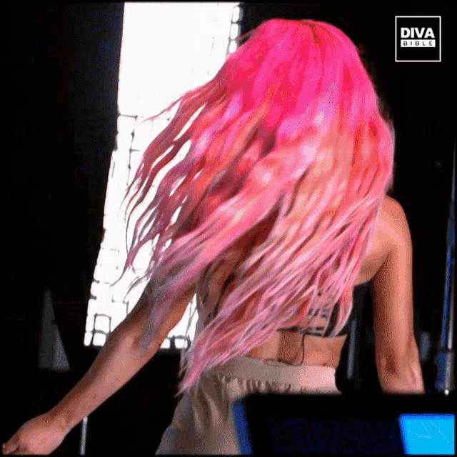 a woman with bright pink hair is dancing in front of a diva girls logo
