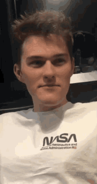 a man wearing a nasa t-shirt is looking at the camera