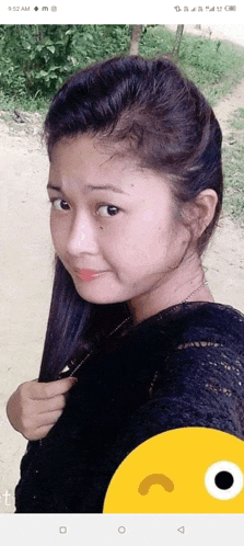 a young girl is taking a selfie with a yellow smiley face in the background .