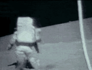 a man in a space suit is walking on the surface of the moon .