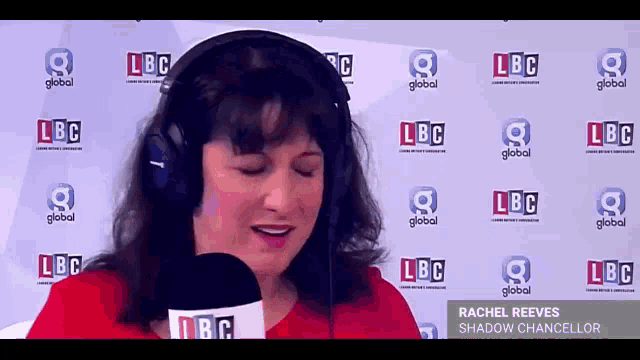 a woman is wearing headphones and holding a microphone in front of a wall that says lbc