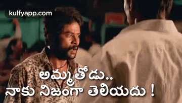 a man with a mustache is talking to another man in a movie in telugu .