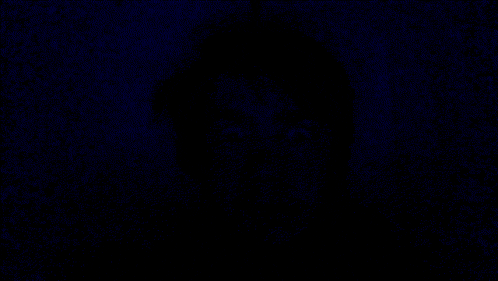 a close up of a person 's face in the dark with blue eyes