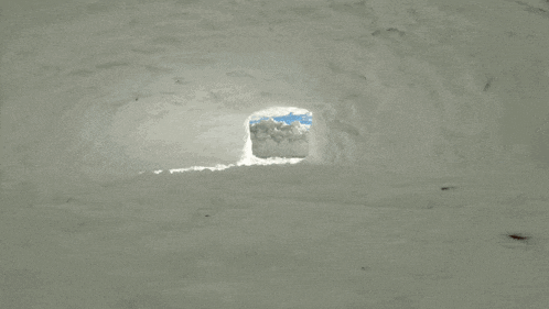 a man in a blue jacket is laying in the snow wearing an adidas beanie