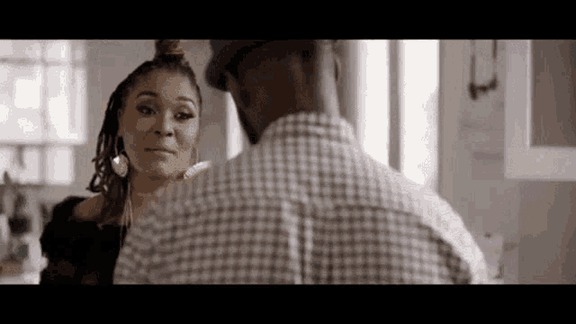 a man and a woman are talking to each other in a kitchen .