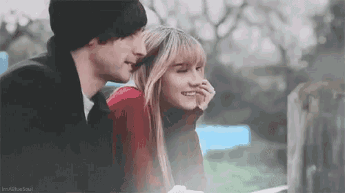 a man and a woman are sitting next to each other in a park .
