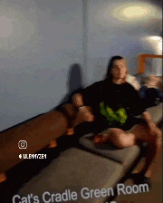 a man is sitting on a couch in a cat 's cradle green room ..