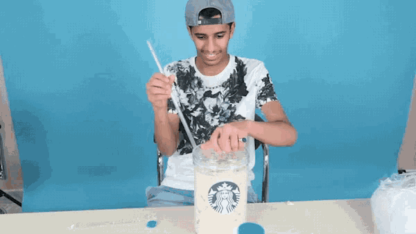 a man is holding a straw over a starbucks cup