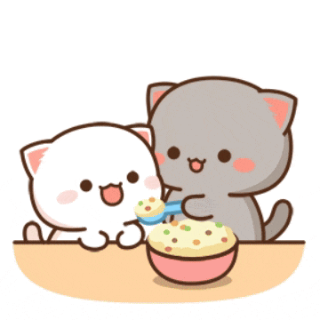 two cats are sitting at a table eating from a bowl with a spoon .