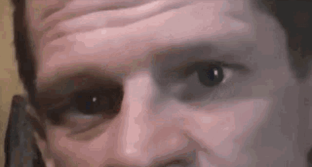 a close up of a man 's eye with a slight smirk on his face .