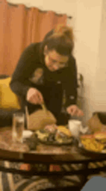 a blurry picture of a woman sitting at a table with a plate of food .