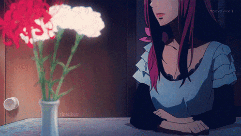 a woman sits at a table with a vase of red and white carnations in front of her tokyo max 1 logo