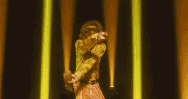 a man in a yellow shirt and orange pants is pointing
