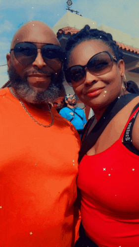 a man and a woman are posing for a picture and the woman is wearing a red tank top