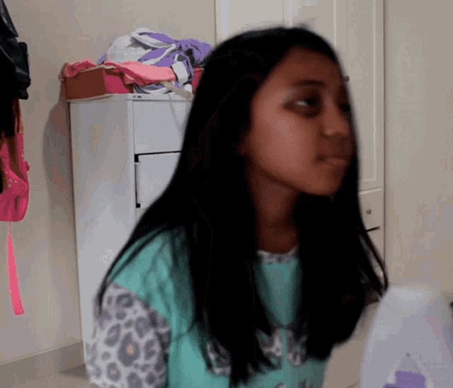a girl with long black hair is wearing a leopard print shirt