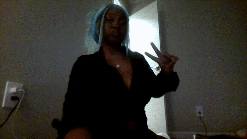 a woman with blue hair and a black shirt giving a peace sign