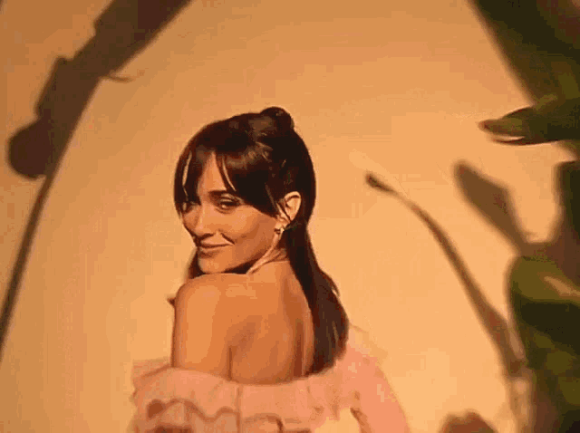 a woman in a pink dress is smiling at the camera .