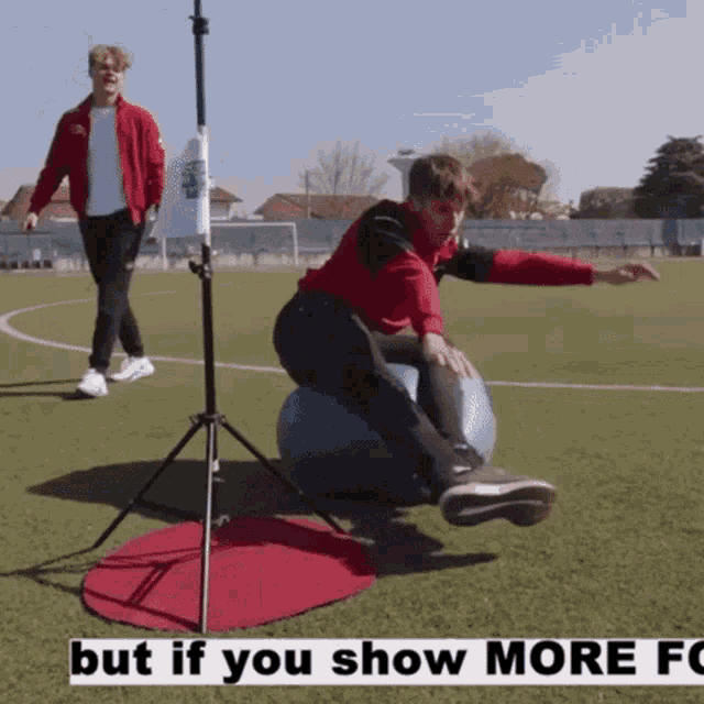 a man is sitting on a blue ball on a soccer field with the words but if you show more fc below him