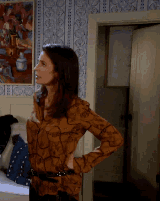 a woman in a brown shirt stands in front of a painting