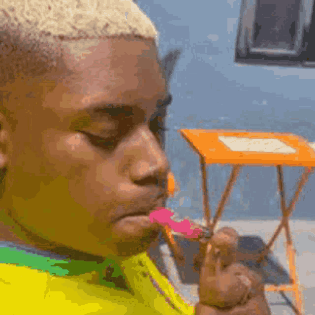 a man in a yellow shirt is eating a candy bar .