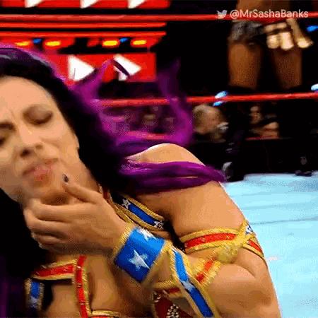 a woman in a wonder woman costume is wrestling in a ring and making a funny face .