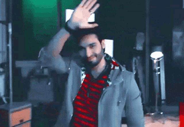 a man with a beard is waving his hand in front of a green screen .