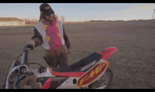 a man standing next to a dirt bike that says fm on the seat