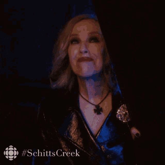 a woman from schitts creek is making a face in a dark room