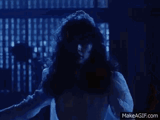 a man in a suit is standing next to a woman in a red dress in a dark room .