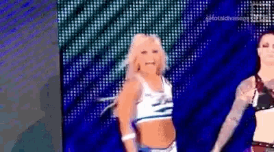 a woman is dancing on a stage in front of a large screen with the words total divas on it .