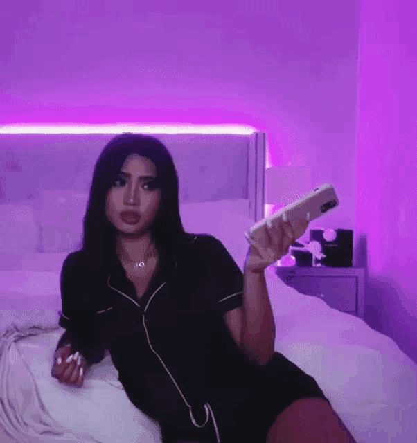 a woman is laying on a bed holding a cell phone in her hand .