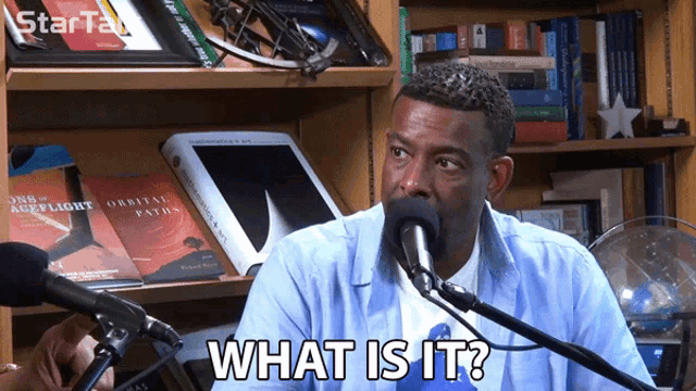 a man talking into a microphone with the words what is it on his face