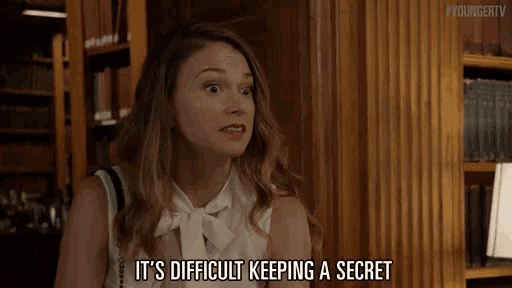 a woman says it 's difficult keeping a secret in front of a bookshelf