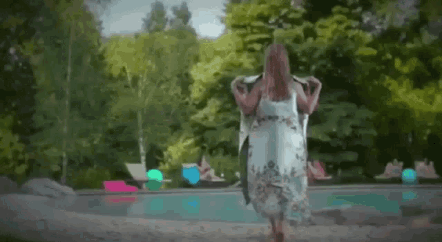 a woman wrapped in a towel is standing next to a pool .