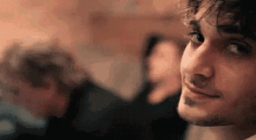 a close up of a man 's face with a beard and a smile on his face .