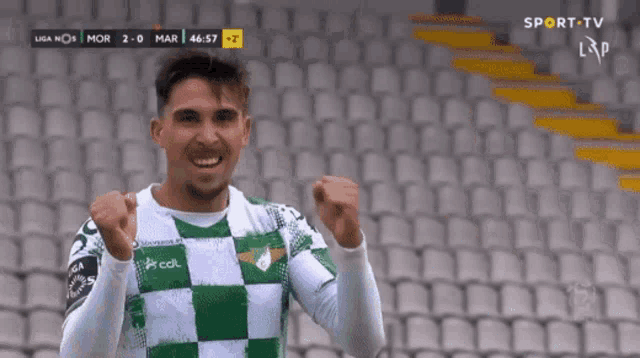 a soccer player in a green and white checkered shirt is celebrating a goal
