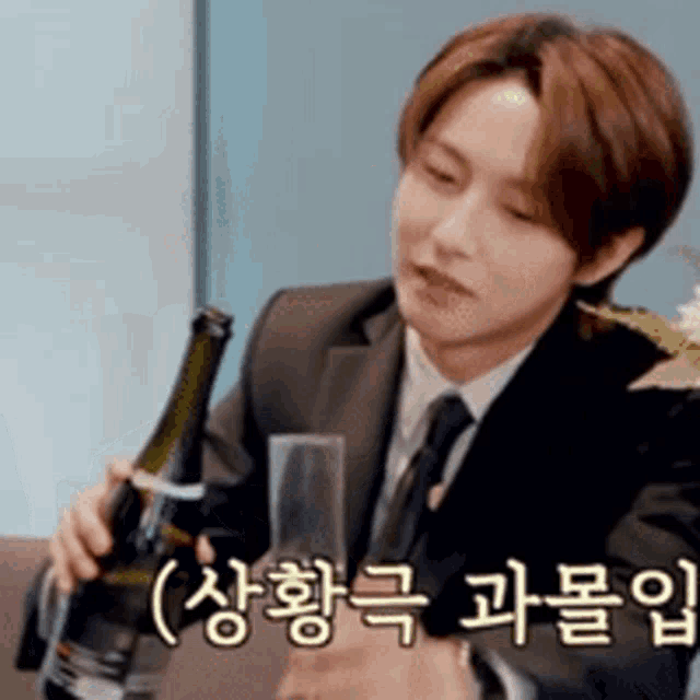 a man in a suit is holding a bottle of champagne and a glass .